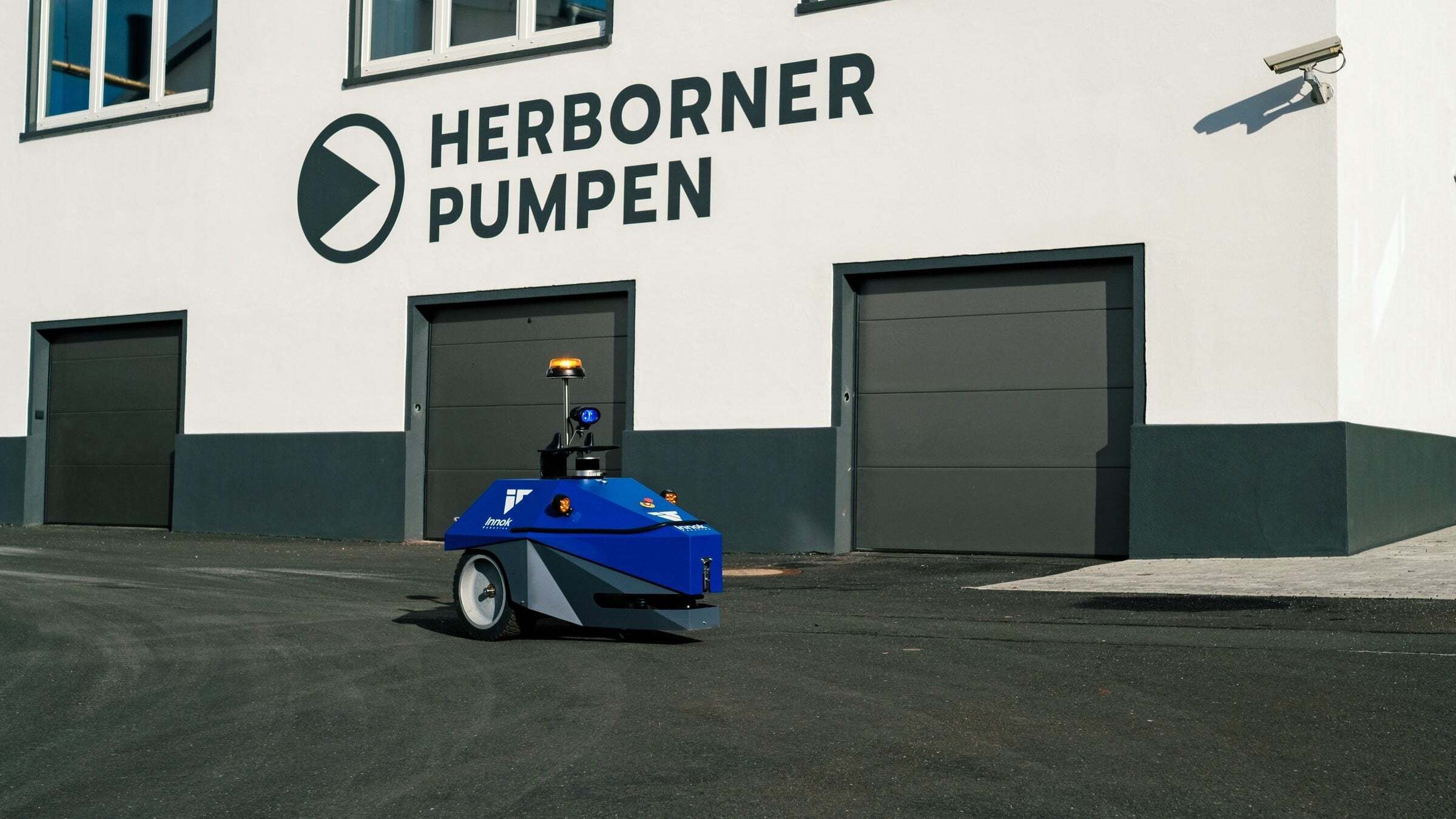 Transportroboter INDUROS vor dem Werksgebäude von Herborner Pumpen – Schwerlasttransport im Kundenvideo
