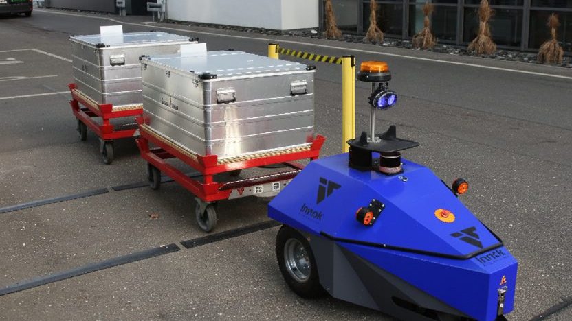 Transportroboter INDUROS als autonomer Routenzug mit zwei Anhängern auf dem Werksgelände