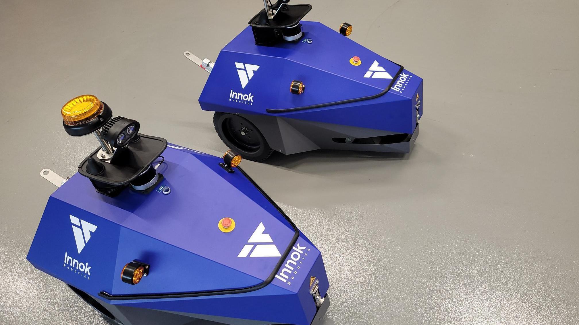 Zwei autonome mobile Roboter INDUROS von Innok Robotics in der Draufsicht auf einem Hallenboden