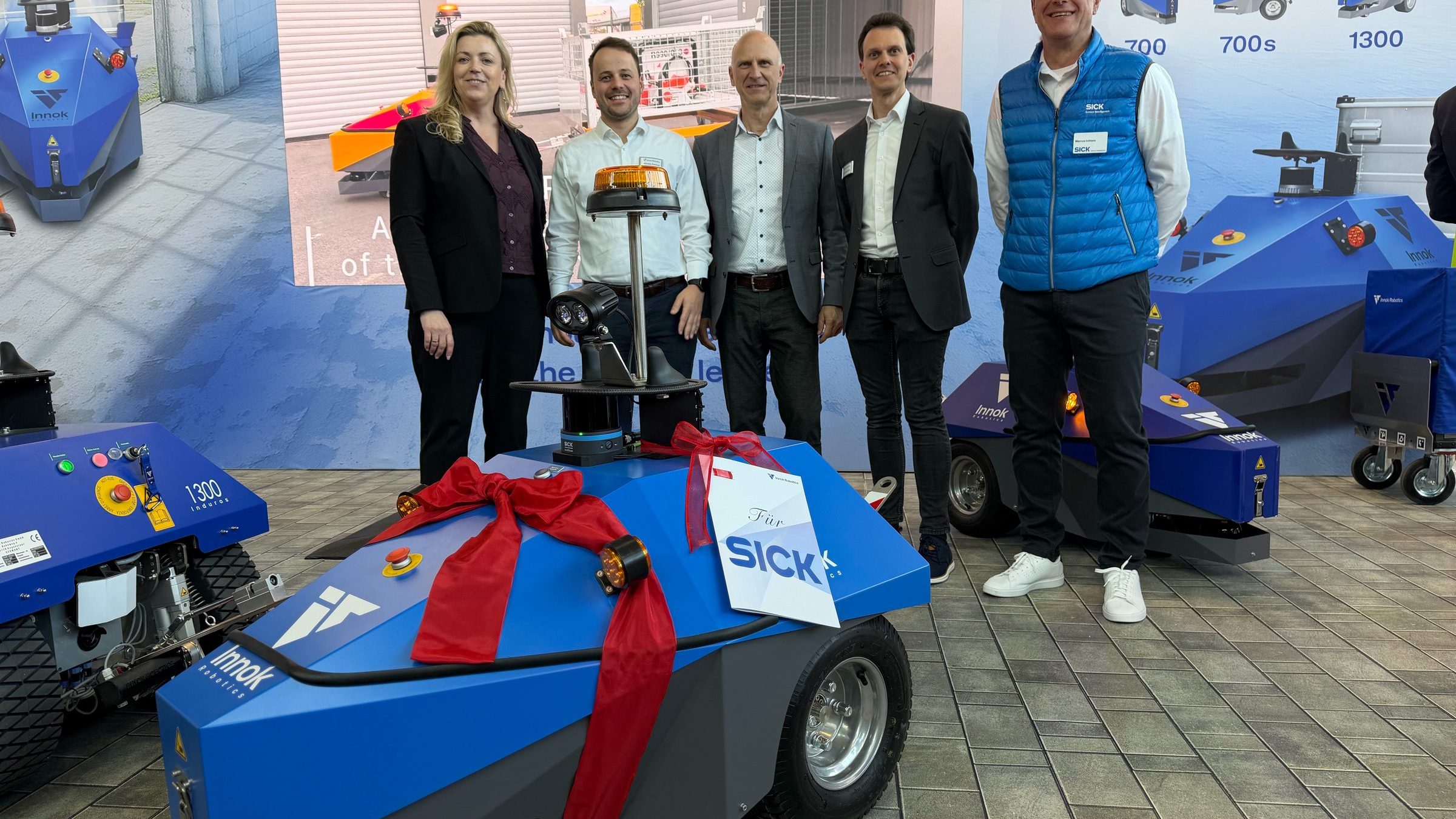 Vertreter von SICK und Innok Robotics bei der Übergabe des Transportroboters INDUROS auf der LogiMAT 2026
