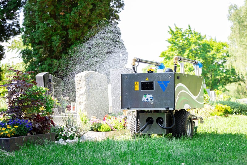 RAINOS Gießroboter bewässert ein Grab auf dem Friedhof